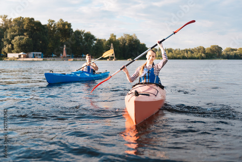 Beaming woman. Beaming blonde-haired woman wearing life vest holding paddles while kayaking