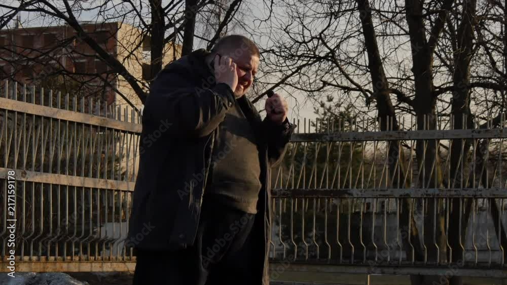A fat man talking on the phone and very nervous on city street. Obesity and stress are cause of myocardial infarction. A fat man talking on the phone and very nervous on city street. Obesity and stress are cause of myocardial infarction.