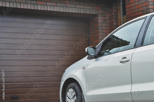 Part of a car parked in front of the garage door