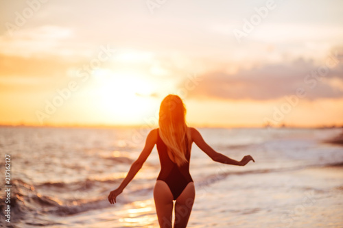 Fototapeta Naklejka Na Ścianę i Meble -  carefree woman dancing in the sunset on the beach.