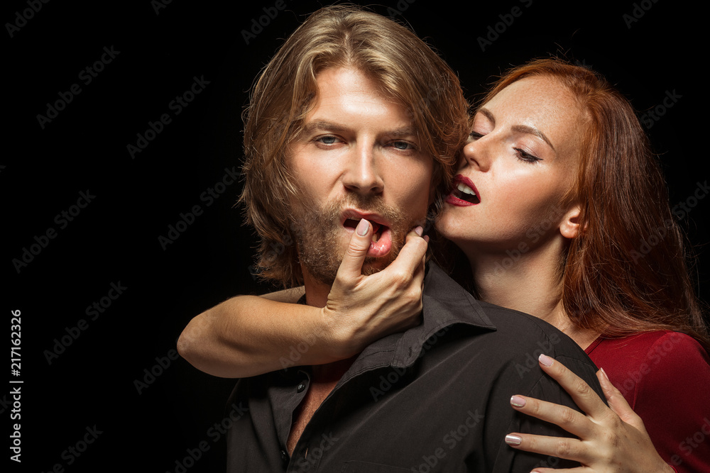 Real passion. Beautiful young loving couple bonding to each other while both standing against black background. Passion, couple, love, sensuality, erotic, sex, relationship concept Real passion. Beautiful young loving couple bonding to each other while both standing against black background. Passion, couple, love, sensuality, erotic, sex, relationship concept