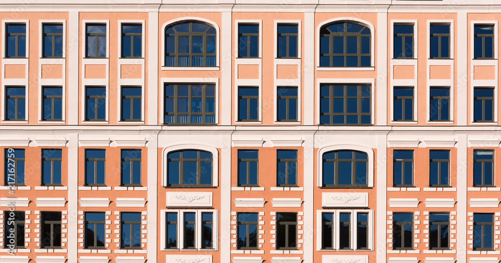 Beautiful facade of a building with yellow walls and white decor on the windows