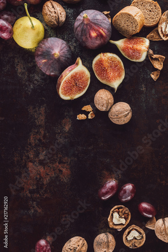 food composition with assorted bread, fruits and hazelnuts on dark surface