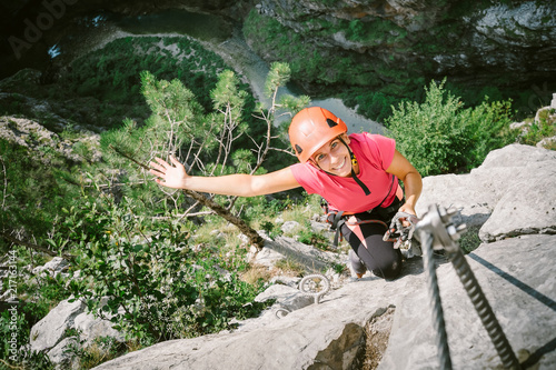 Young happy woman who is climbing along a via ferrata