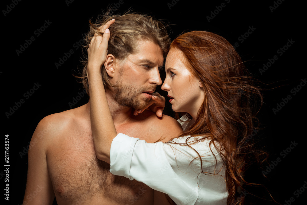 Real passion. Beautiful young loving couple bonding to each other while both standing against black background. Passion, couple, love, sensuality, erotic, sex, relationship concept Real passion. Beautiful young loving couple bonding to each other while both standing against black background. Passion, couple, love, sensuality, erotic, sex, relationship concept