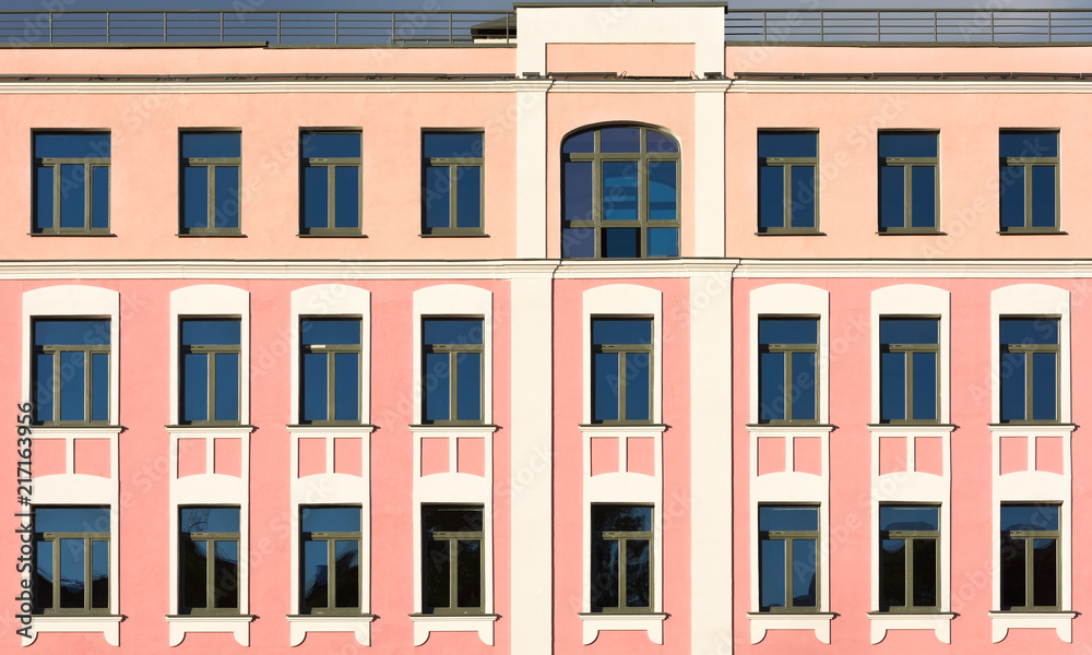 The facade of the old building with pink walls and white decor on the windows
