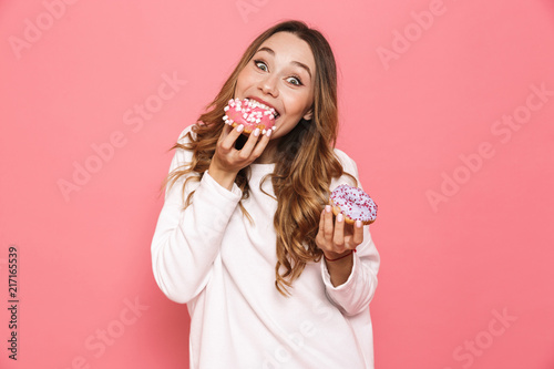 Portrait of a happy young woman eating donuts