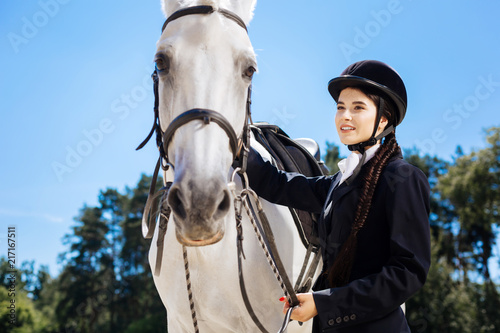 Beautiful rider. Beautiful dark-eyed female rider with fishtail standing near her gentle white horse