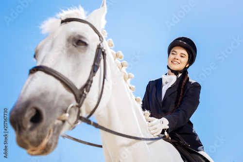 Sitting on horse. Horsewoman wearing white gloves and blue jacket sitting on her white horse