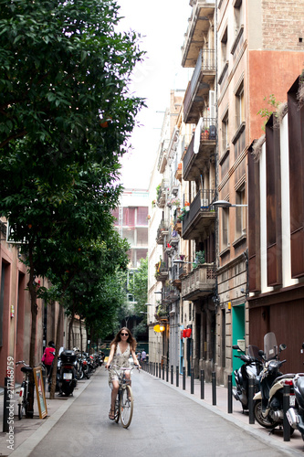 Happy smile young female traveler tourist ride a bike in city center of Barcelona. Traveling in Spain © tatyanasuyarova