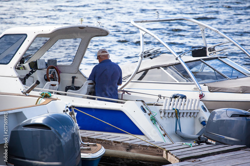 an elderly man aboard his yacht in port
