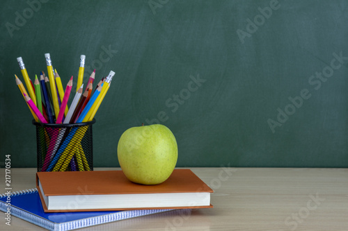 manzana en libros con lápices y pizarra vacía, regreso a la escuela