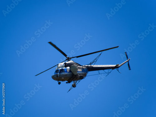A helicopter of agricultural aviation is flying in the blue sky. Helicopter for spraying fertilizers and pesticides