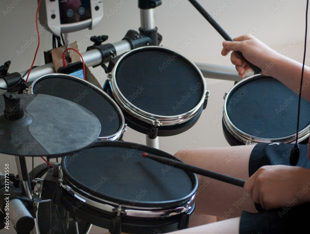 Fotografie unrecognized boy playing electronic drums with black drumsticks