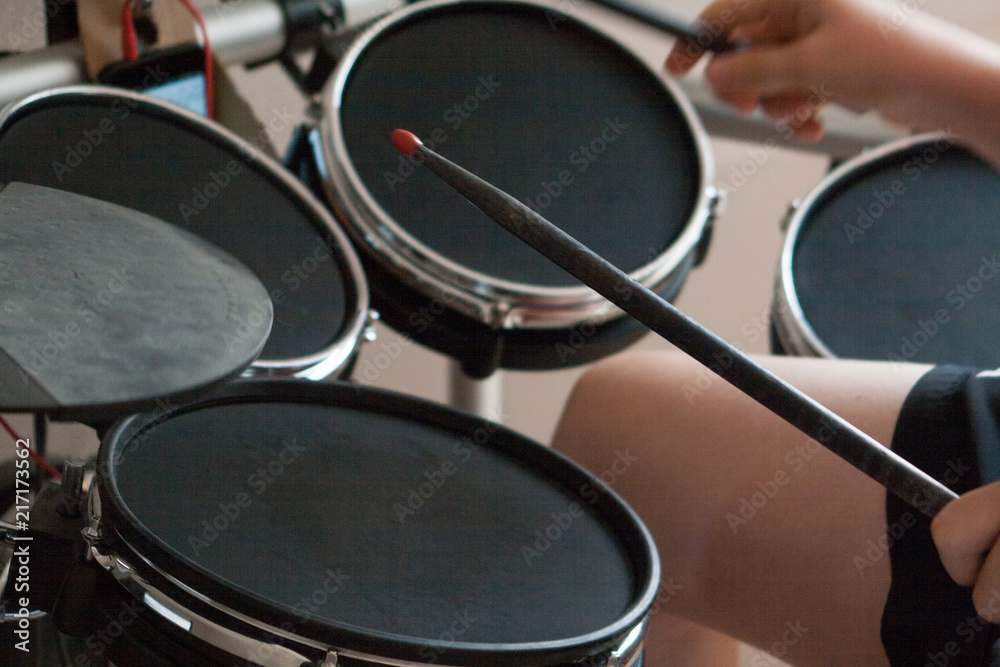 Fotografie unrecognized boy playing electronic drums with black drumsticks