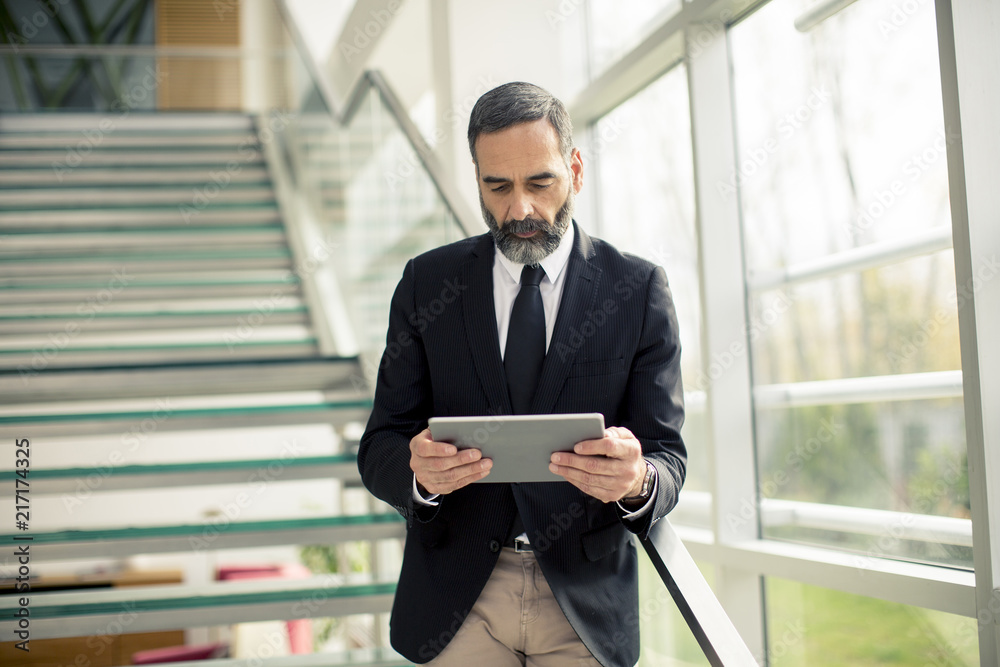 Fototapeta premium Handsome senior businessman with digital tablet in the modren office