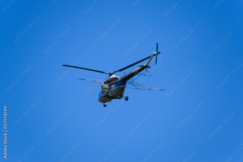 A helicopter of agricultural aviation is flying in the blue sky. A helicopter of agricultural aviation is flying in the blue sky.