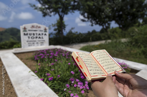 read a Koran ,holy book for Muslims on the cemetery visit to the festival. 