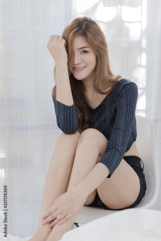 Sexy Asian woman smile and sitting on bed in the room Sexy Asian woman smile and sitting on bed in the room