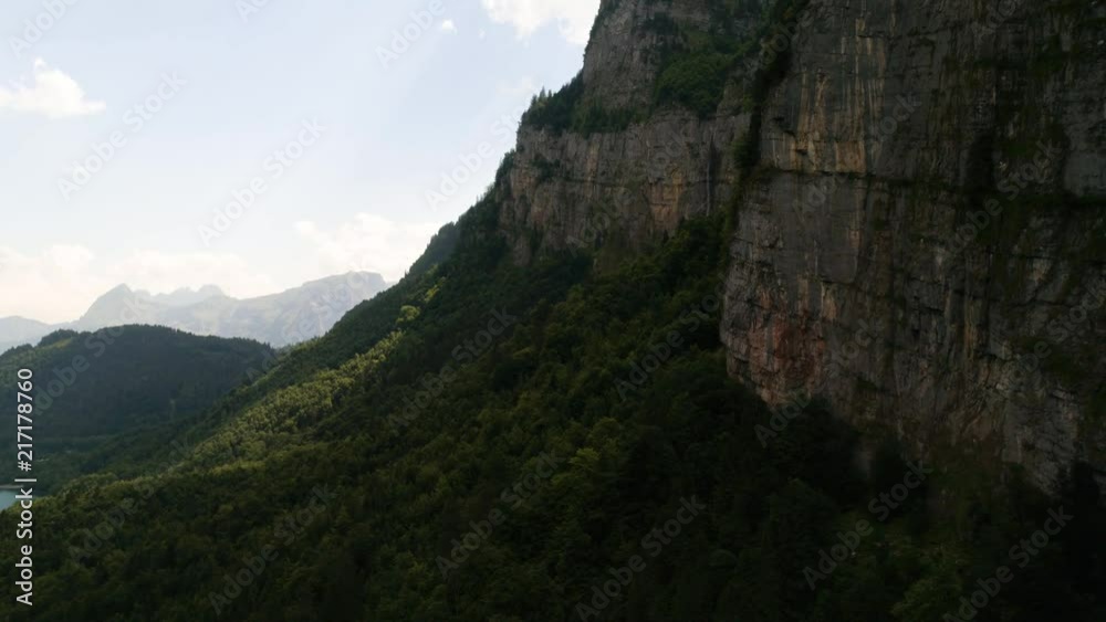 aerial view of mountain scenery flying close to cliff with lake and forest, klontalersee switzerland aerial view of mountain scenery flying close to cliff with lake and forest, klontalersee switzerland