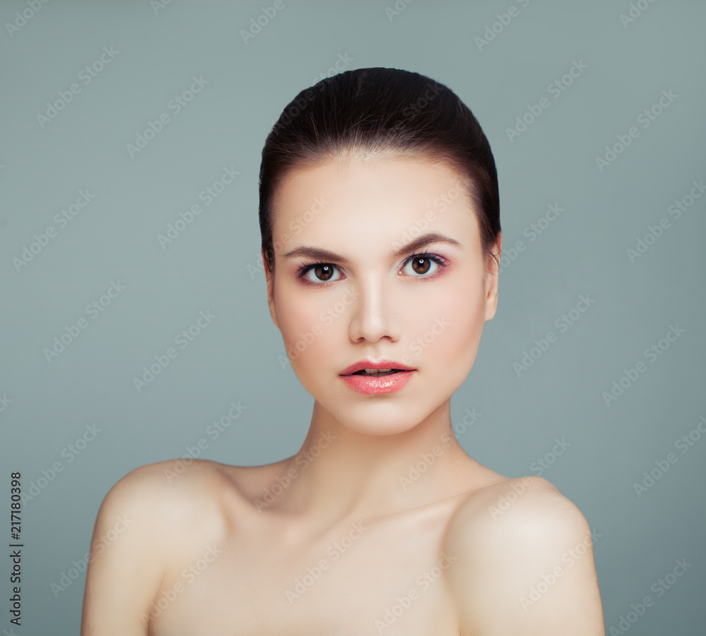 Young woman face. Pretty model girl with natural makeup and perfect skin on blue background. Cosmetology, skincare and wellness concept Young woman face. Pretty model girl with natural makeup and perfect skin on blue background. Cosmetology, skincare and wellness concept