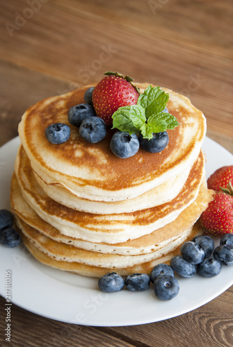 Pancakes with strawberry and blueberry jam, delicious dessert for breakfast, rustic style, wooden background.