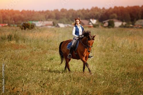 Young woman jockey gallop brown horse strolling across forest.