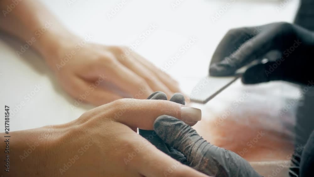 Closeup shot of a beautician applying nail polish to female nail in a nail salon. Woman getting nail manicure, spa treatments. Closeup shot of a beautician applying nail polish to female nail in a nail salon. Woman getting nail manicure, spa treatments.