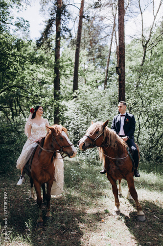 Forest walk of the newlyweds on horseback. © dimadasha