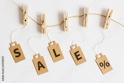 Brown cardboard price tags with sign sale hanging on wooden clothes clips on white background