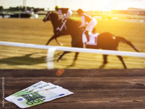 Fototapeta Euro money on the background of a TV on which show jumps on horses, sports betti