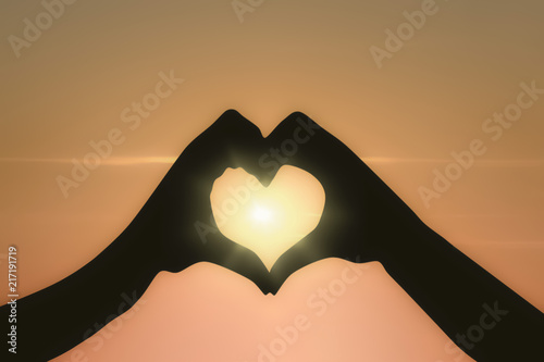 Hands of man and woman showing heart shape with sunset in the background