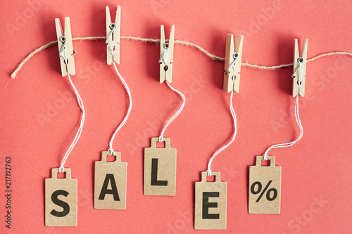 Cardboard price tags with sign sale hanging on wooden clothes clips on red background