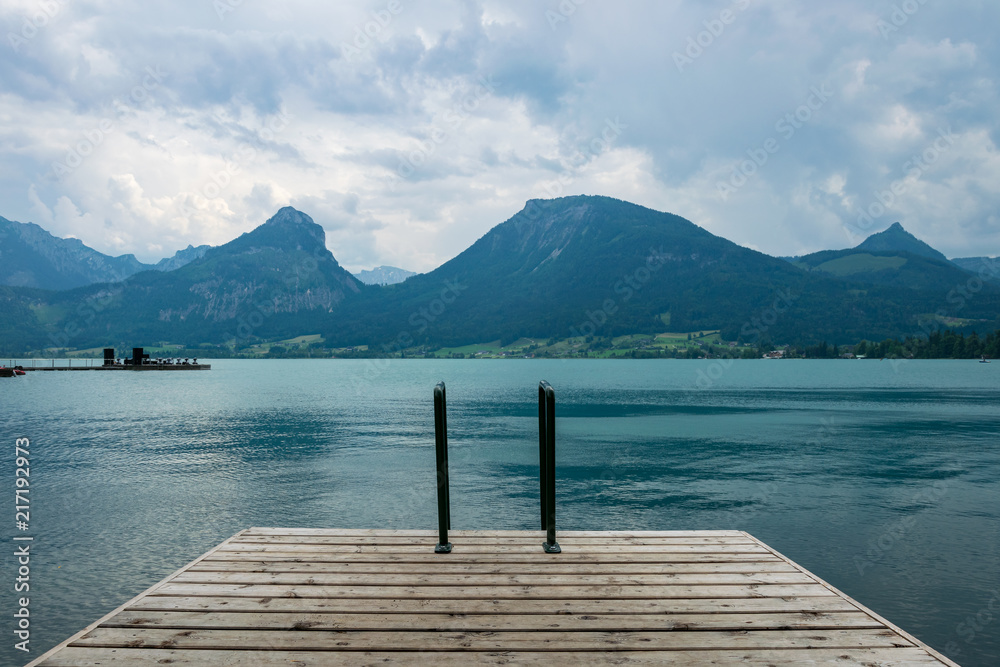 Footbridge at the Wolfgangsee in Austria with mountains in the background and clouds on the sky