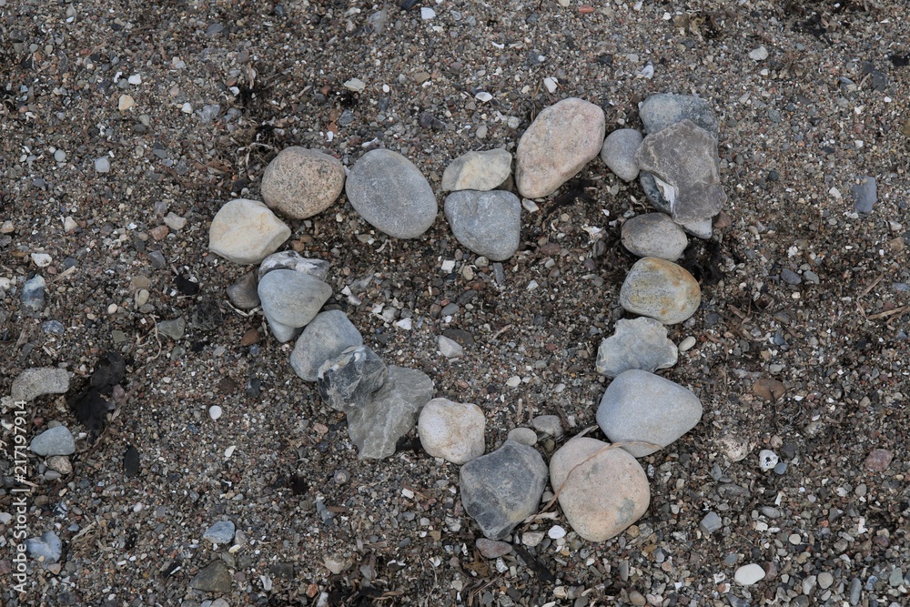 a heart build out of stones as a background at the beach - obrazy, fototapety, plakaty 
