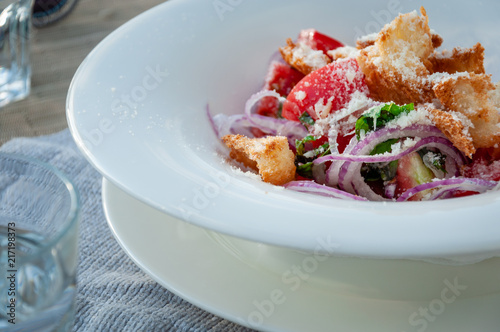 Tuscan Panzanella, traditional Italian salad with tomatoes and bread. With glass of water photo