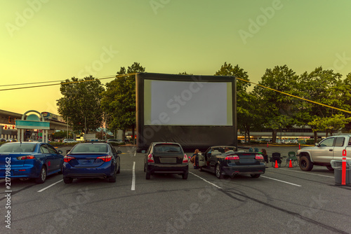 Obraz na płótnie Spectators at a car parking lot with cars, an inflatable screen of the summer cinema, waiting for a movie w salonie