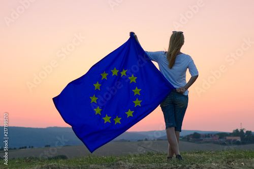 Woman holding European Union flag and watching  sunset