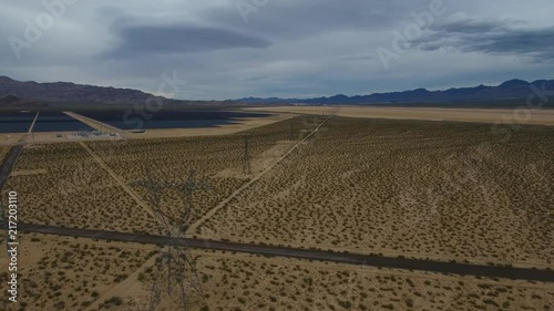 Power lines in the desert with soloar panel farm in the background. photo
