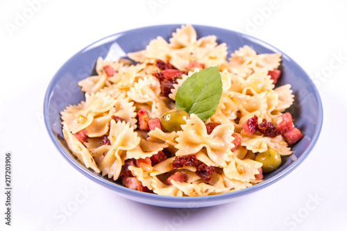 Farfalle pasta with sun dried tomato, ham and olives decorated with fresh mint