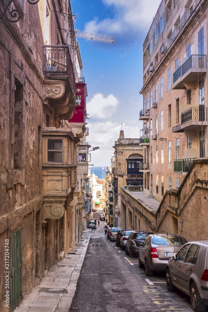 Old narrow street with colorful balconies in historical part of Valletta in Malta