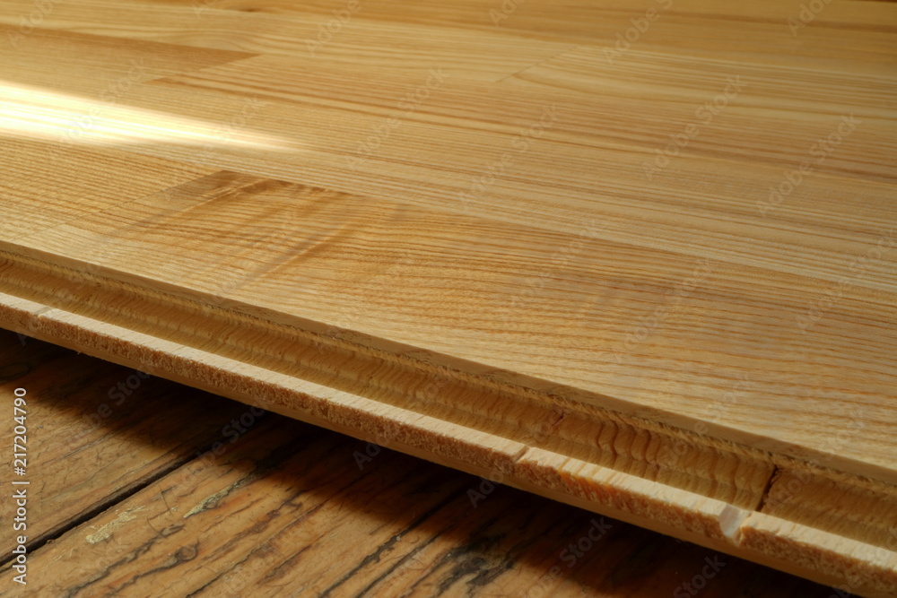 An image of an old wooden floor and a new parquet board.