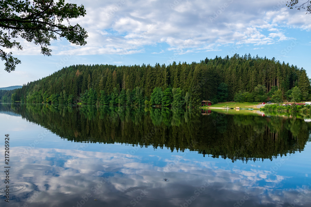 Lake with Reflection on the Water and Trees in the background and Clouds on the sky in the bavarian forest
