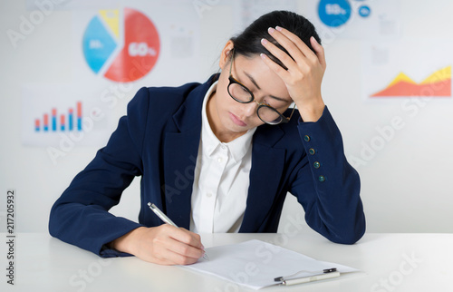 Asian businesswoman wearing suit working at the office, Thinking and writing down on blank paper sheet at the office, Thinking and pay attention and curious situation. Business and finance concepts. photo