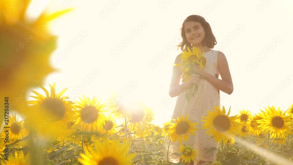 Vidéo Stock Happy little girl teen smelling a sunflower on the field in ...
