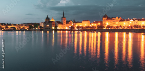 Historical buildings of Smetana Embankment reflected in the water of Vltava River on summer evening. Prague, Czech Republic.