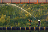 Men water the grass with water from a hose