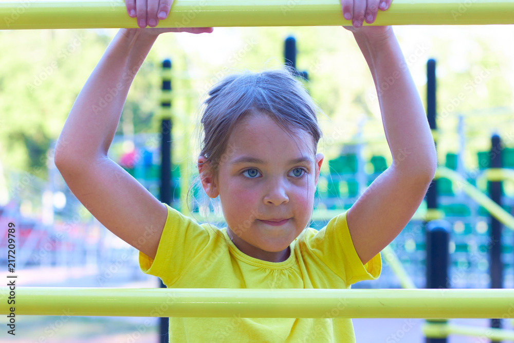 Fototapeta premium A little girl on the playground climbs the stairs.