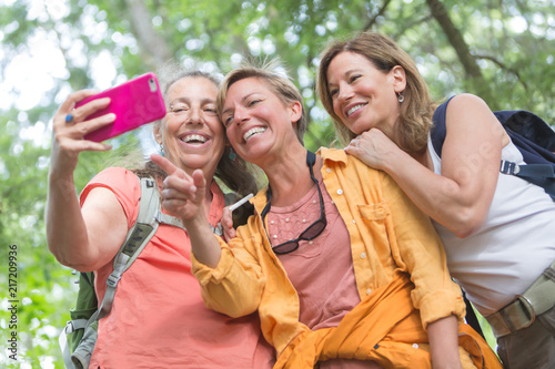 Happy senior and middle aged active women stop for a selfie photo while hiking.