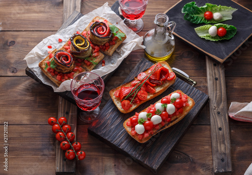 Bruschetta with tomato, basil and mozzarella cheese on wooden board. Traditional italian appetizer or snack, antipasto photo